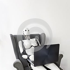 Robot working with laptop while sitting in armchair