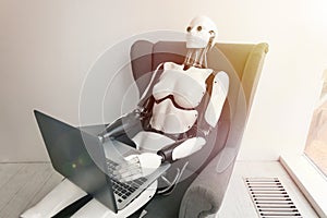 Robot working with laptop while sitting in armchair. Artificial intelligence robotic concept