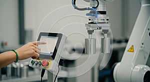Robotic Arm Control Panel Hand Interacting with Touchscreen Display in a Factory Setting