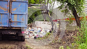 Robotic arm of garbage truck taking gabbage