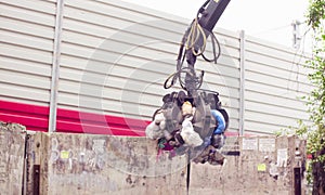 Robotic arm of garbage truck taking gabbage