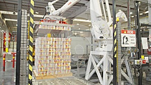 Robotic arm placing canned food for packaging in a warehouse in a food production facility