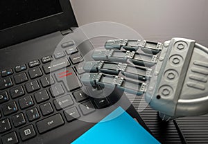 Robotic hand approaching keypad of black notebook.
