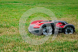 Robotic lawn mower on grass, side view. Garden modern remote technology