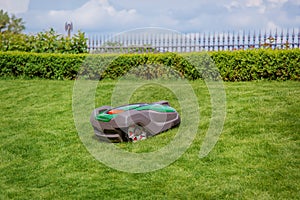 Robotic lawn mower on grass, side view. Garden modern remote technology