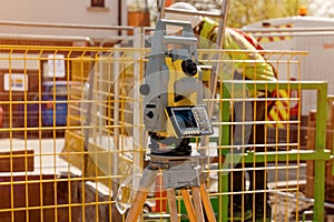 Robotic total station set by construction site engineer next to manhole box for position control, during new deep drainage manhole