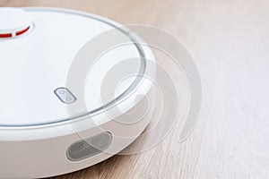 Robotic vacuum cleaner cleaning laminate wooden floor. smart cleaning technology. housework and technology concept. Close up, copy
