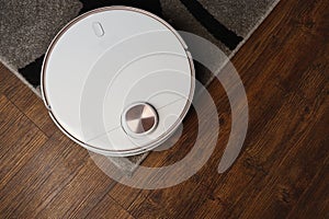 Robotic vacuum cleaner on laminate wood floor and the carpet in living room