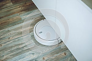 Robotic Vacuums, Robot Mops. Smart home. Automatic robotic vacuum cleaner on laminate wood floor, smart cleaning