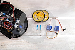 Robotics parts. Servo, screwdriver lying on a wooden table. view