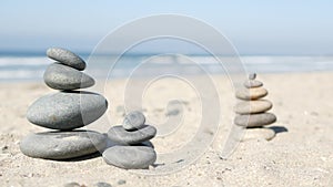 Rock balancing on ocean beach, stones stacking by sea water waves. Pyramid of pebbles on sandy shore