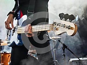 Rock band performs on stage. Bassist in the foreground.