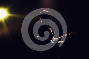 Rock band performs on stage. Guitarist plays solo. silhouette of guitar player in action on stage in front of concert crowd.