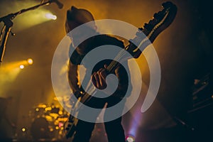 Rock band performs on stage. Guitarist plays solo. silhouette of guitar player in action on stage in front of concert crowd.