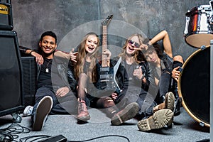 Rock band sitting on floor while resting after rehearse