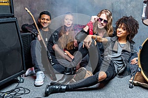 Rock band sitting on floor while resting after rehearse in studio