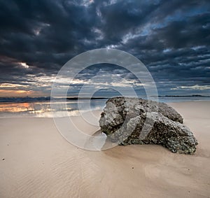 Rock on the beach with dramatic sky on square form