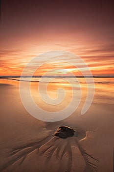 Rock on beach at sunset