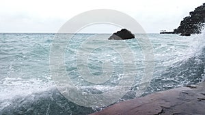 rock and big wave crasing over the seawall