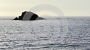 Rock in the calm sea at sunset