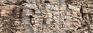 Rock cliff face background. Toned. Wild stone protruding crumbling layered blocks in quarry. Abstract texture for stone