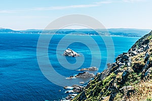 Rock cliff in the ocean with blue water and sunny sky