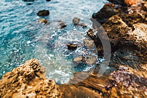 Rock cliff, rocky seashore, beach and blue water in sea ocean. Summertime nature