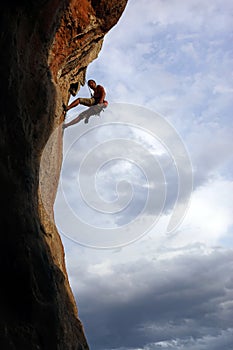 Rock climber against cloudy sky background