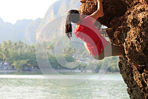 Rock climber climbing on seaside cliff