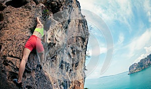 Rock climber climbing on seaside cliff