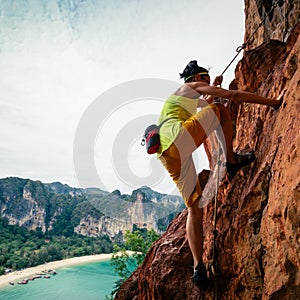 Rock climber climbing on seaside cliff