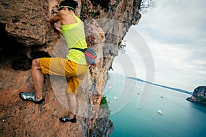 Rock climber climbing on seaside cliff