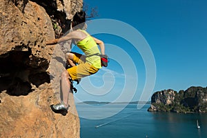 Rock climber climbing at seaside cliff