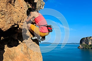 Rock climber climbing at seaside cliff