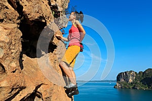 Rock climber climbing at seaside cliff