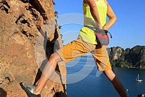 Rock climber climbing at seaside cliff
