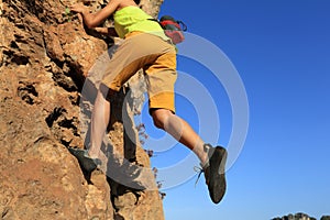 Rock climber climbing at seaside cliff