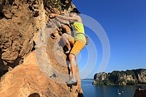Rock climber climbing at seaside cliff