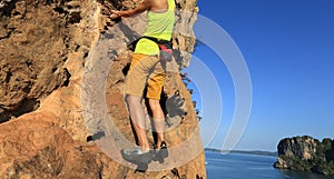 Rock climber climbing at seaside cliff