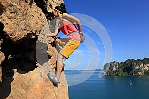 Rock climber climbing at seaside cliff