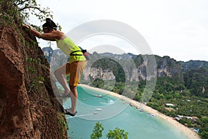 Rock climber climbing at seaside cliff