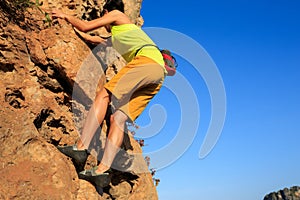 Rock climber climbing at seaside cliff