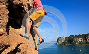 Rock climber climbing at seaside cliff