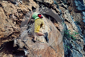 Rock climber climbing on seaside steep cliff