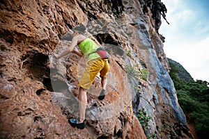 Rock climber climbing on seaside steep cliff