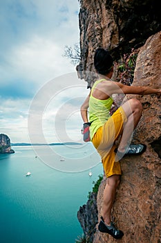 rock climber climbing on seaside steep cliff