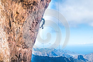 Rock climber climbing up overhanging cliff