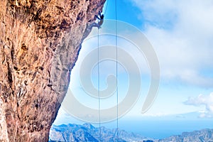 Rock climber climbing up overhanging cliff