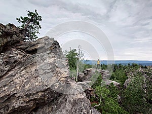 Rock climber on the edge of a cliff in the forest.