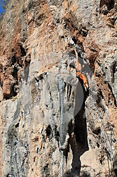 Rock climber girl leaging climbing route on natural rock